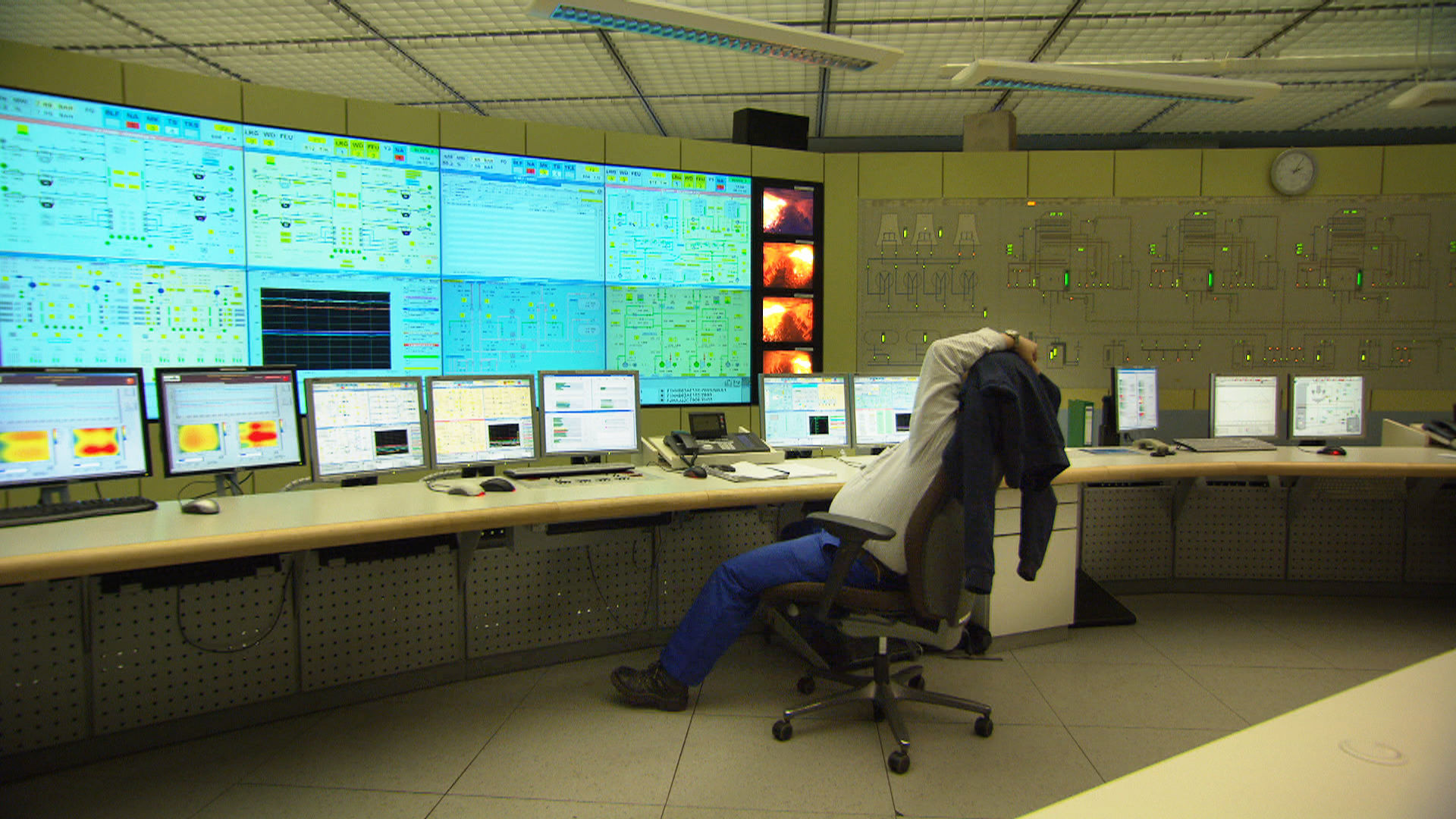 Leitwarte eines Kraftwerks mit großer Monitorwand, ein Mitarbeiter lehnt sich im Stuhl zurück
