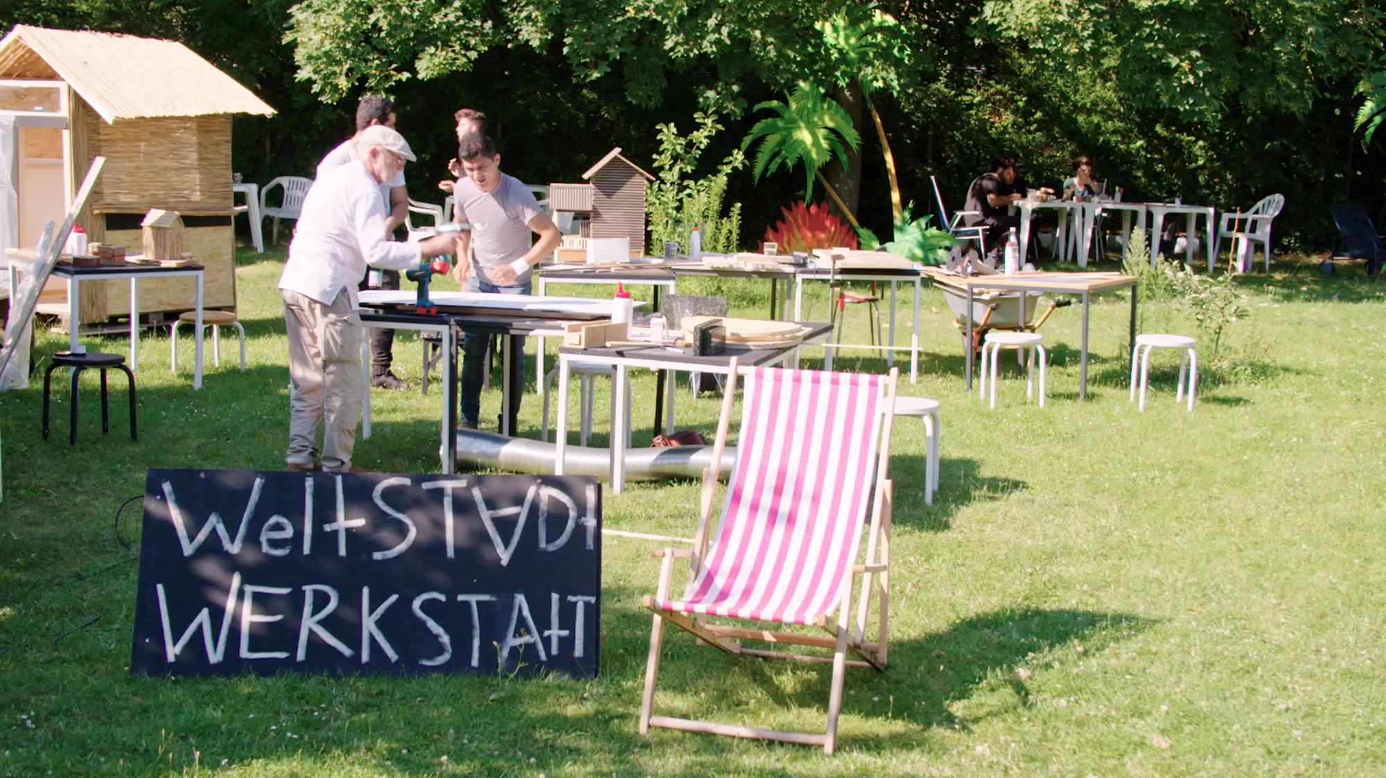 Gartenwerkstatt mit Basteltischen und Tafel „Weltstadt Werkstatt“