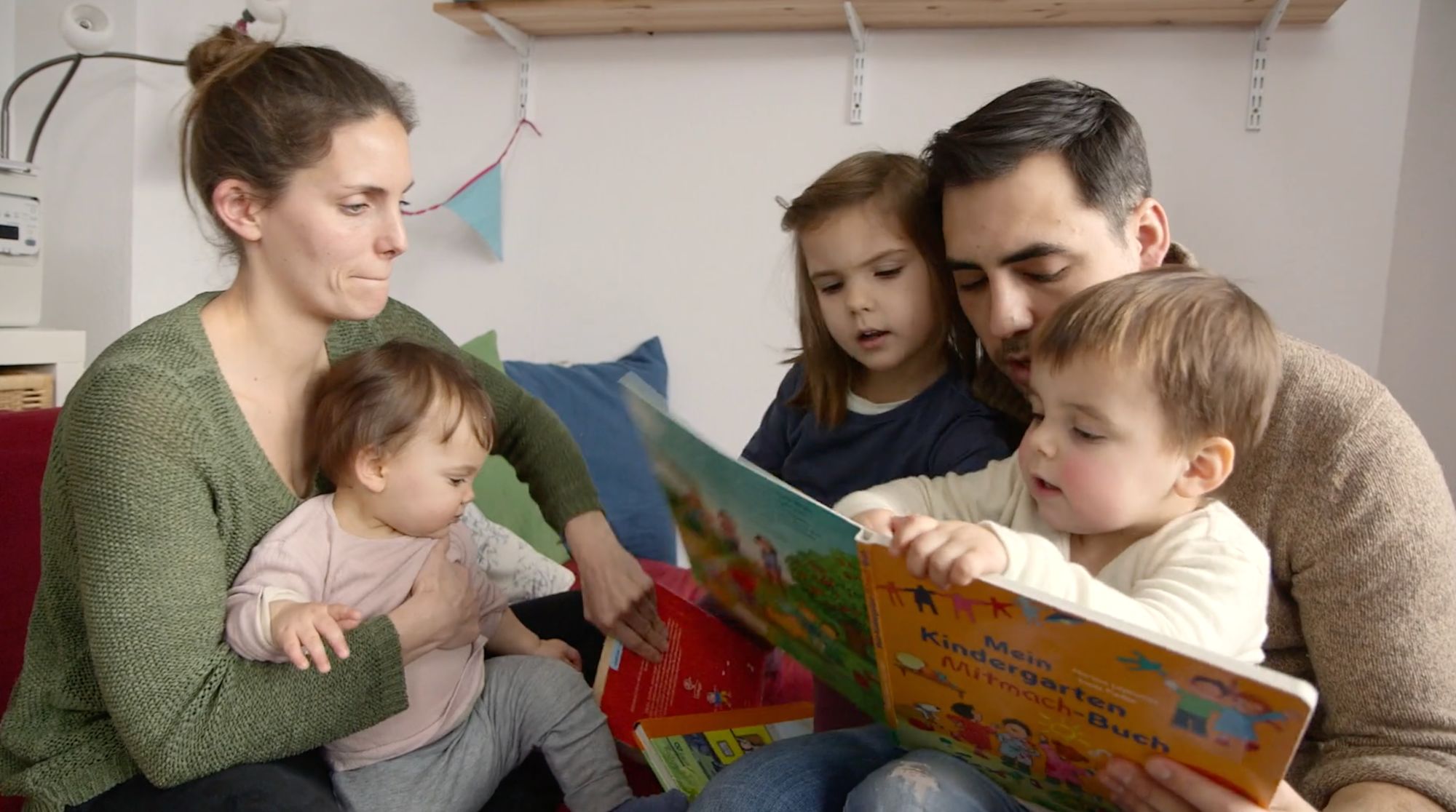 Familie liest gemeinsam im Bilderbuch „Mein Kindergarten Mitmach-Buch“