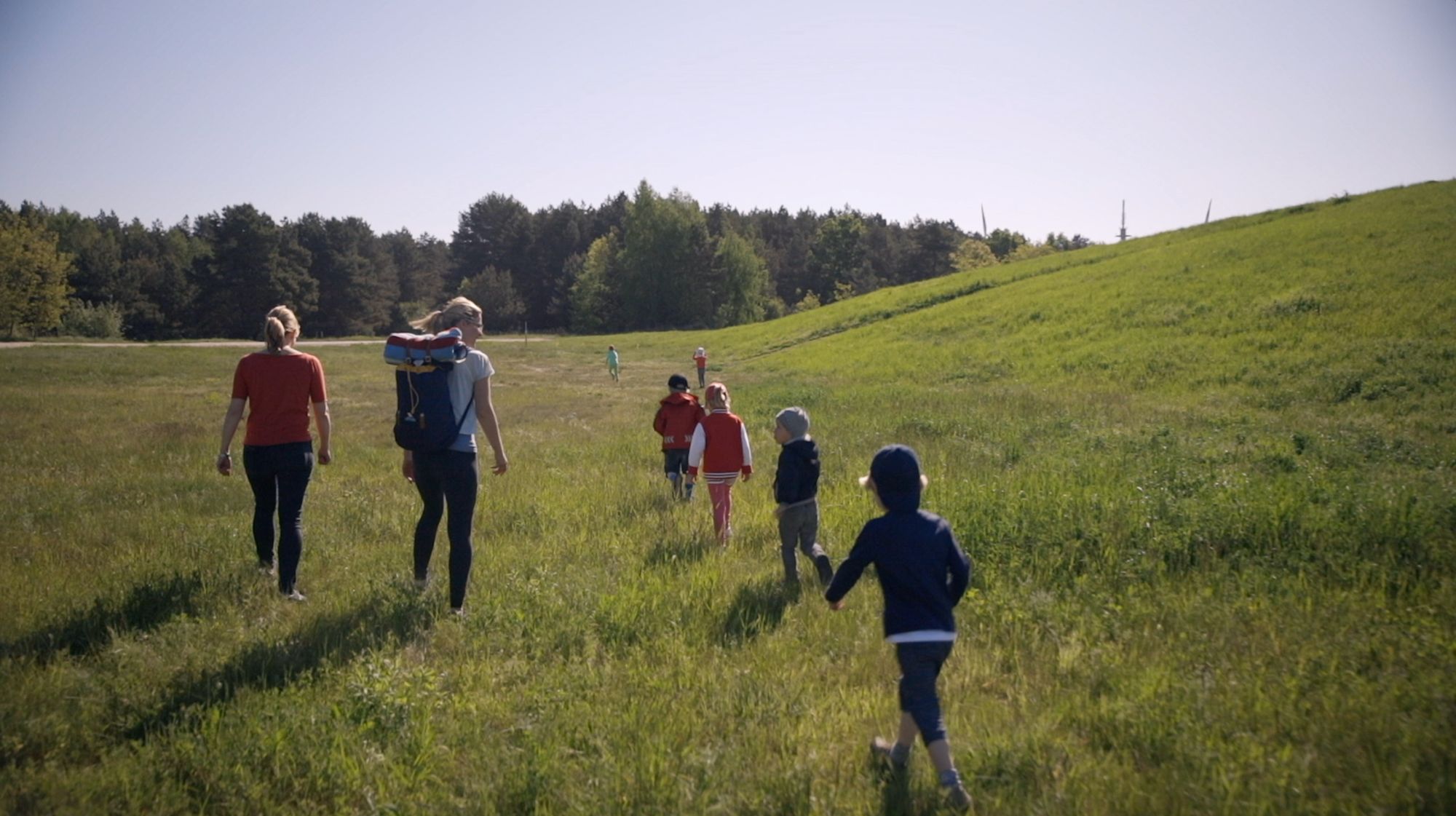 Gruppe mit Kindern und zwei Betreuerinnen wandert über eine Wiese