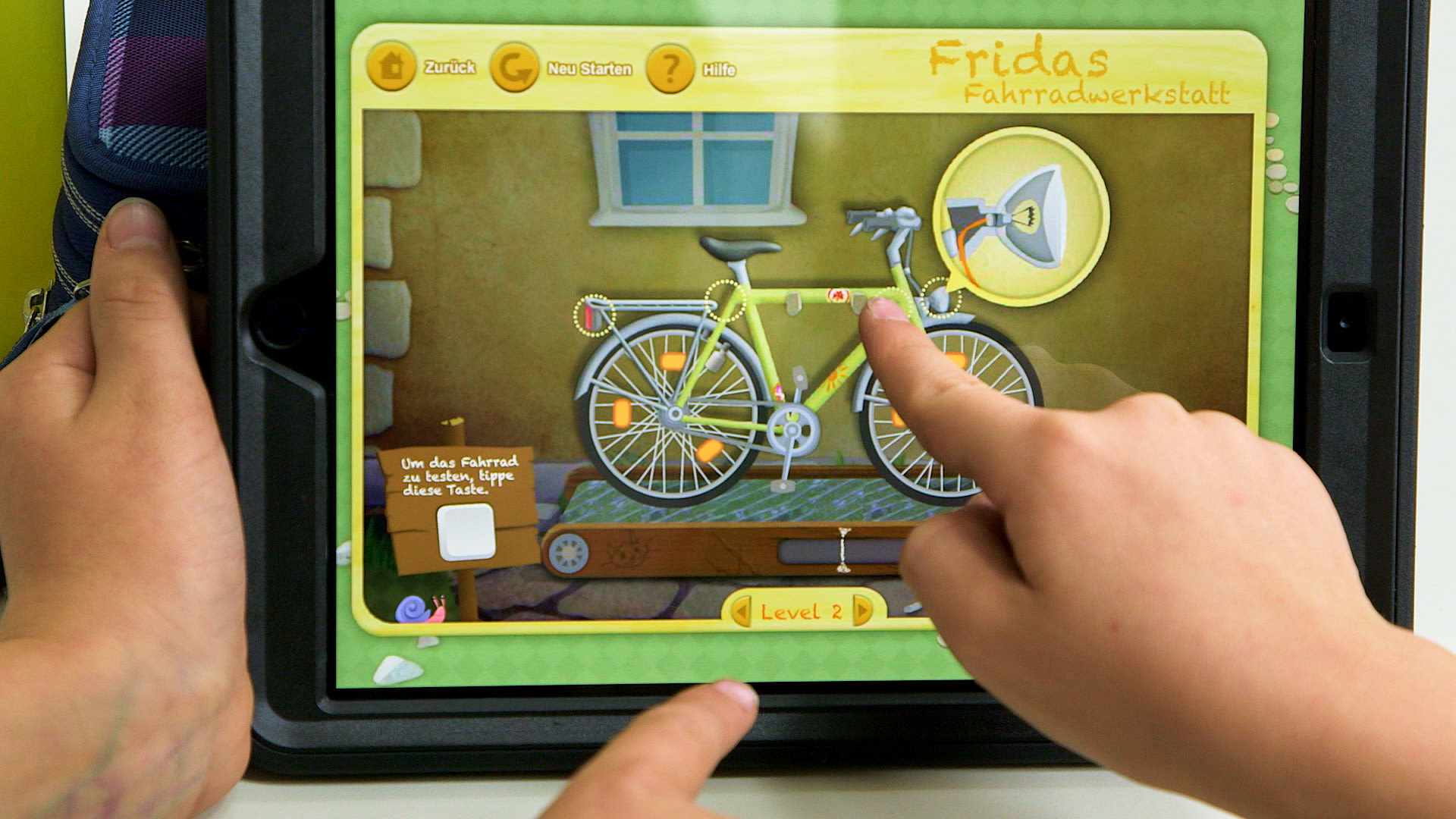Bildschirmaufnahme der Lern-App „Fridas Fahrradwerkstatt“ mit einem Fahrrad zum Zusammenbauen