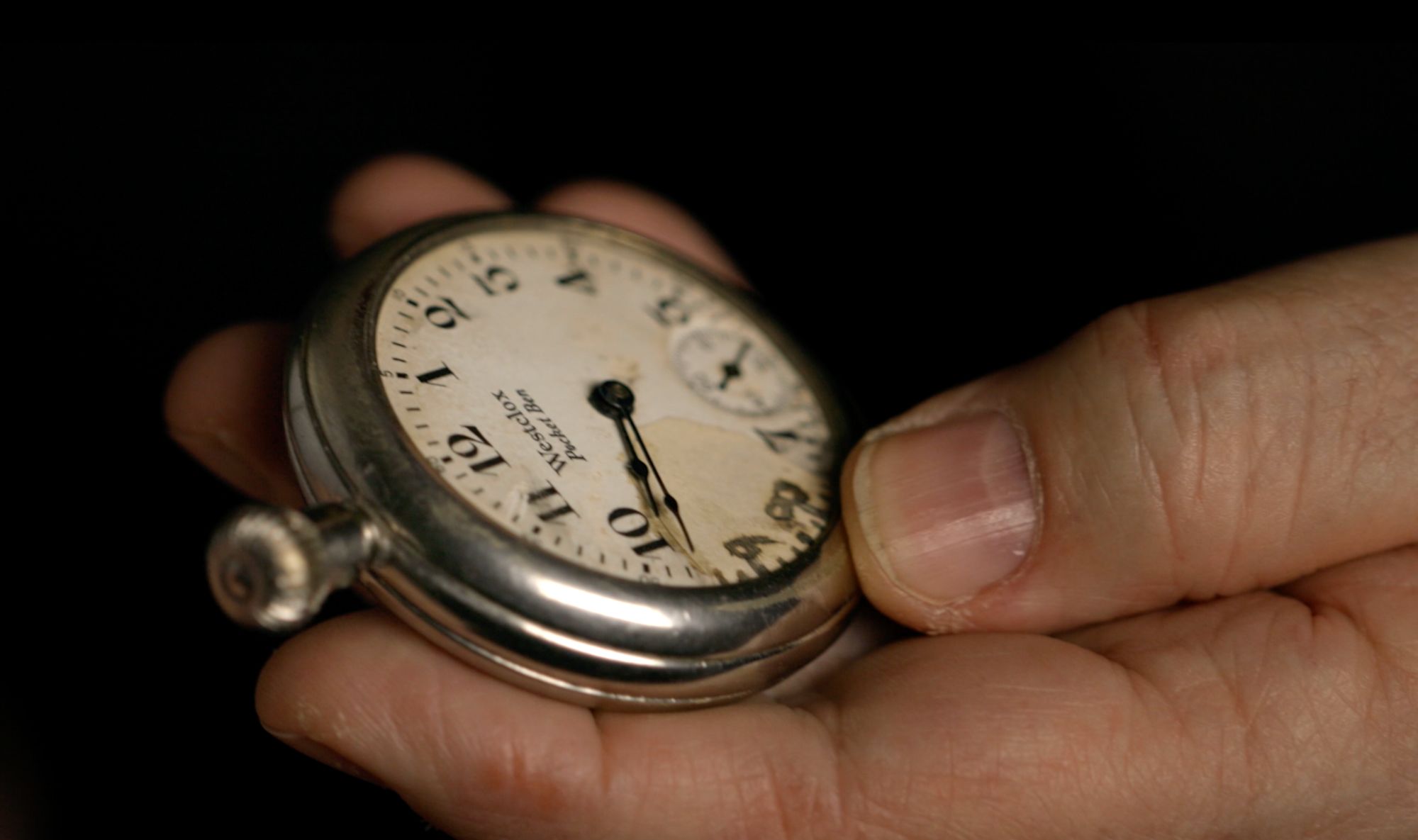 Nahaufnahme einer Hand mit einer alten Taschenuhr der Marke Westclox