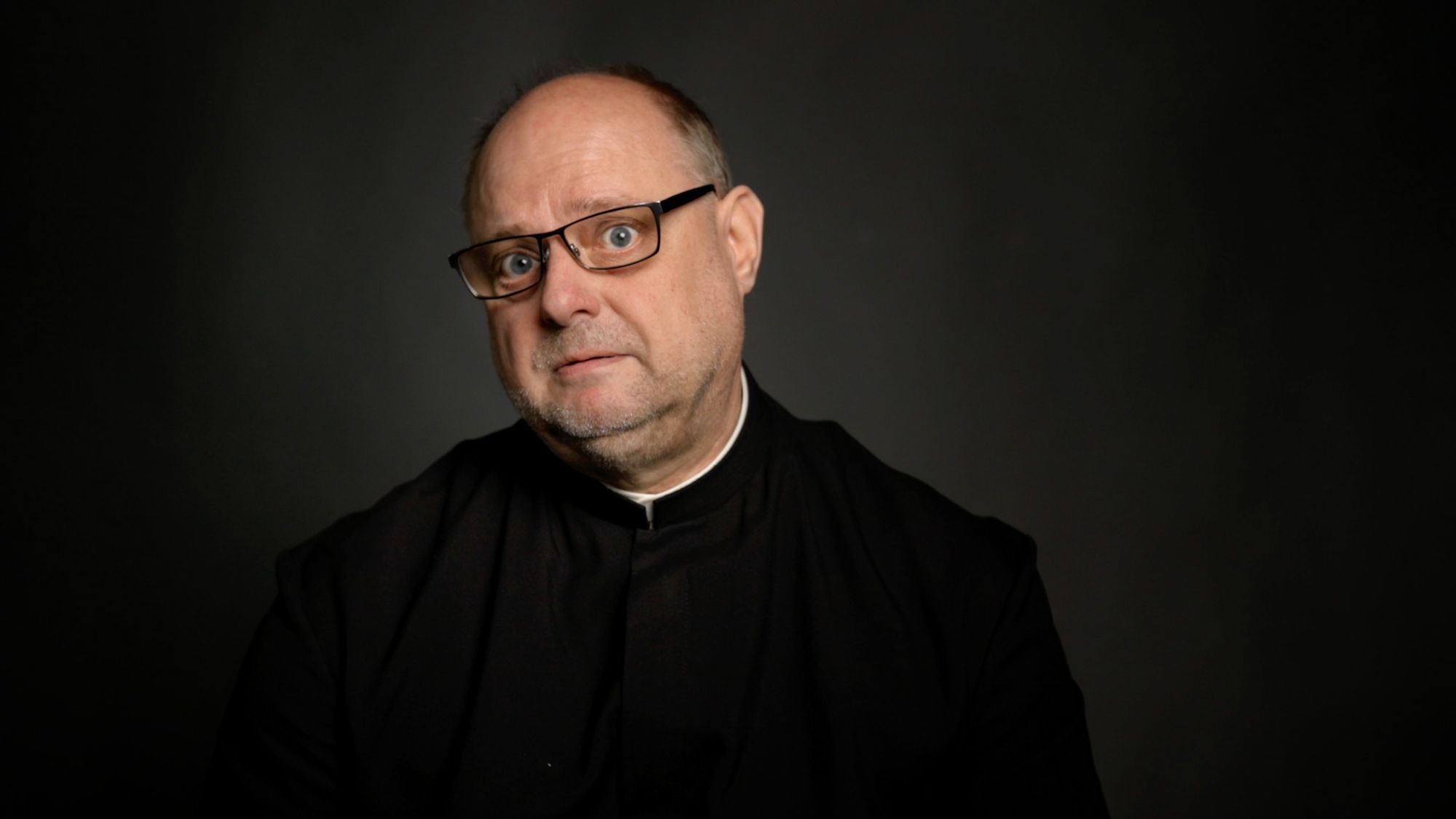 Porträt eines Geistlichen mit Brille und weißem Kragen, überraschter Gesichtsausdruck