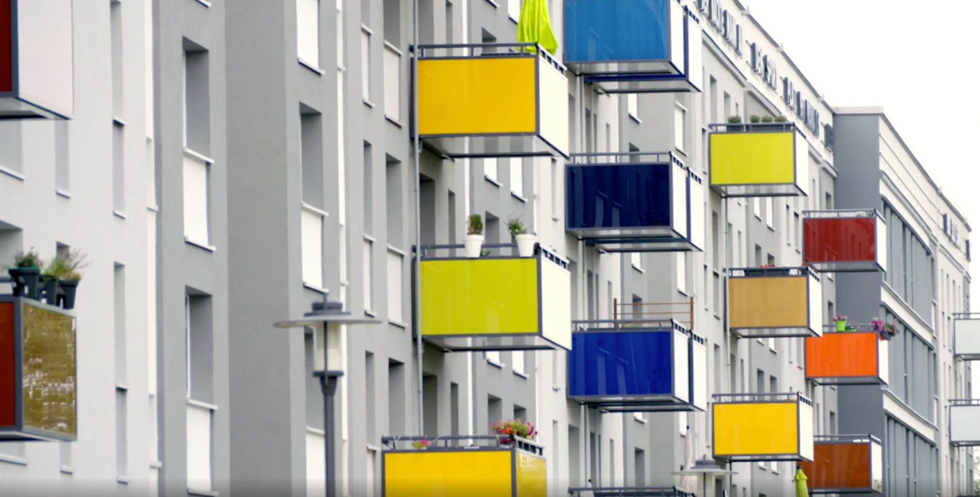 Bunte Balkonverkleidungen in Gelb, Blau und Rot an einer Hausfassade
