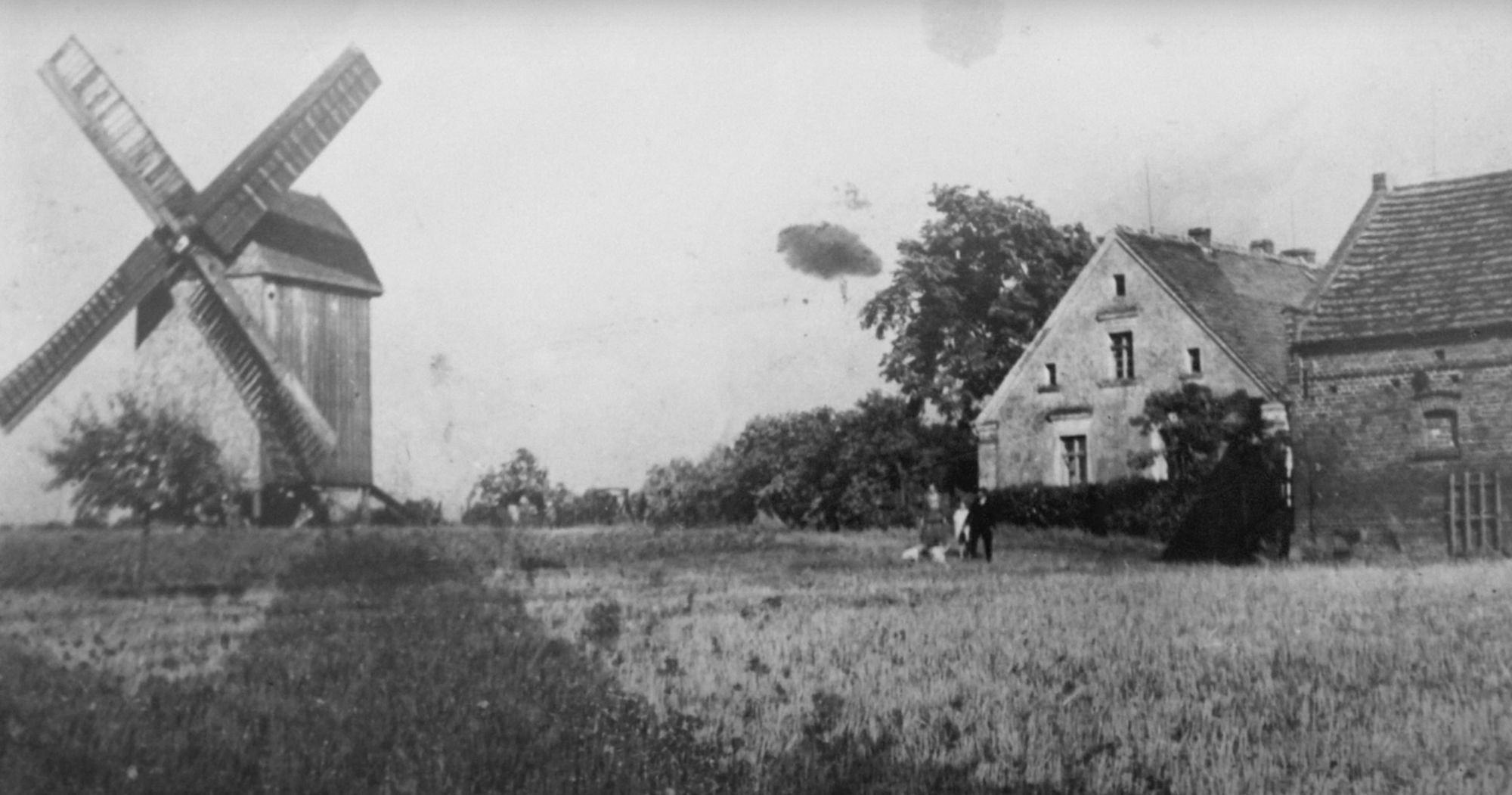 Historische Schwarz-Weiß-Aufnahme der Bockwindmühle und eines Gehöfts mit zwei Personen