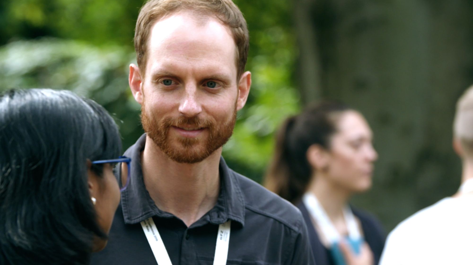 Porträt eines lächelnden Mannes mit Konferenz-Lanyard im Freien