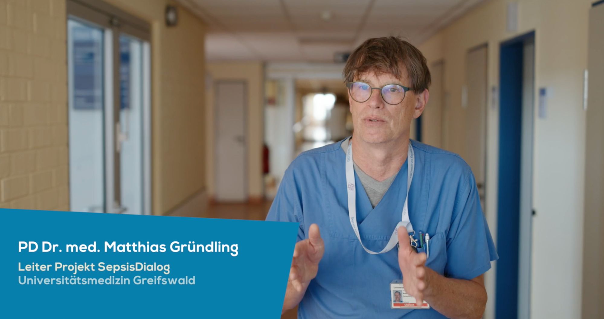 Arzt im Klinikflur im Gespräch, Einblendung „PD Dr. med. Matthias Gründling“