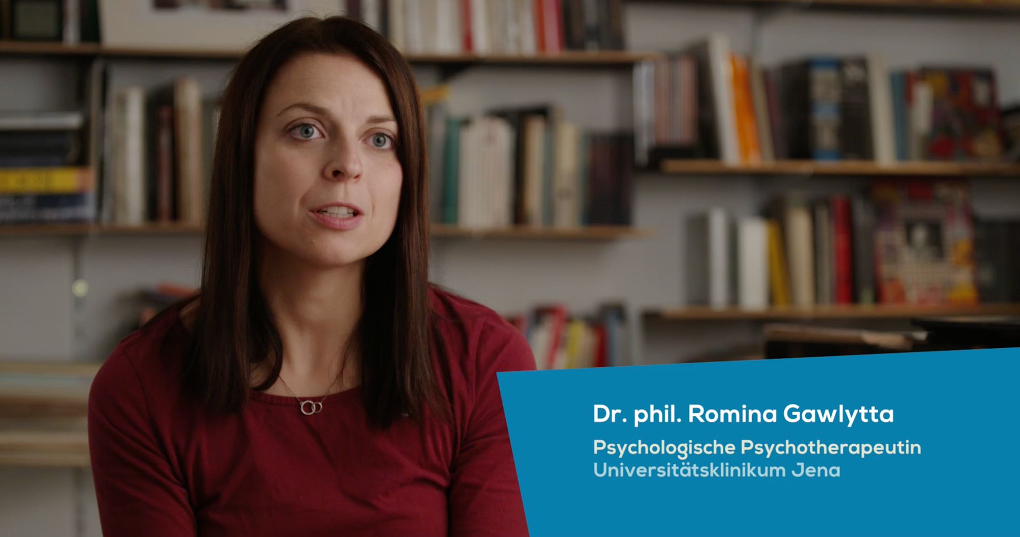 Frau vor einem Bücherregal im Interview, Einblendung „Dr. phil. Romina Gawlytta“