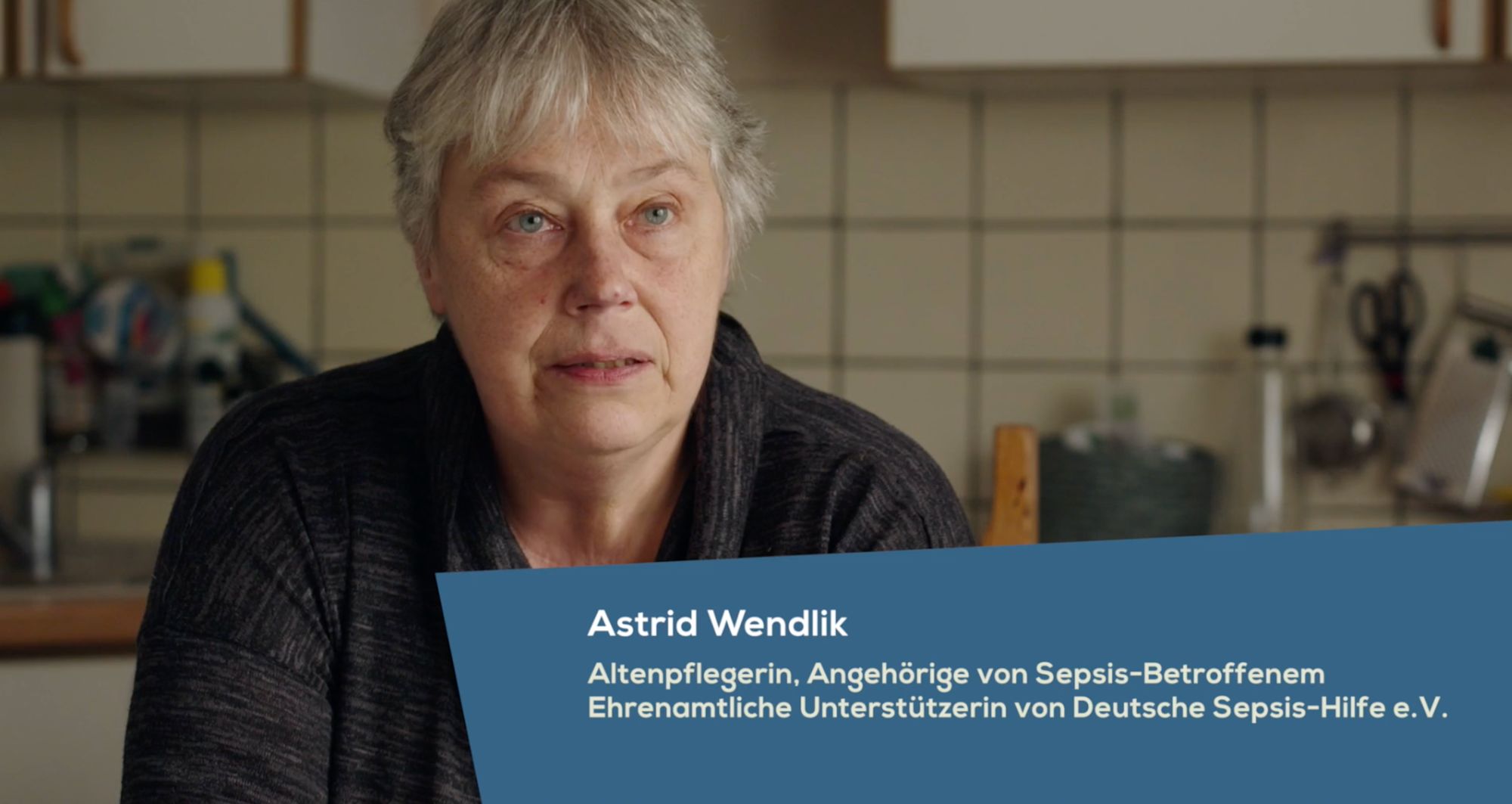 Frau in einer Küche im Interview, Einblendung „Astrid Wendlik, Altenpflegerin“