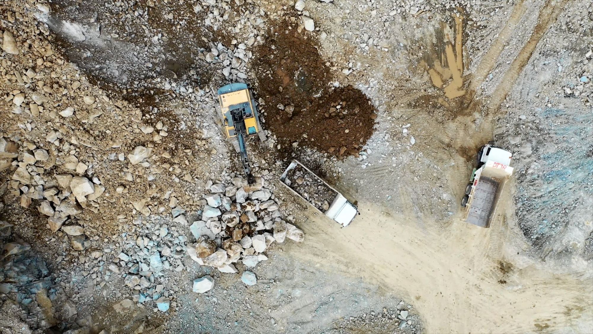 Luftaufnahme eines Steinbruchs mit Bagger und Lastwagen