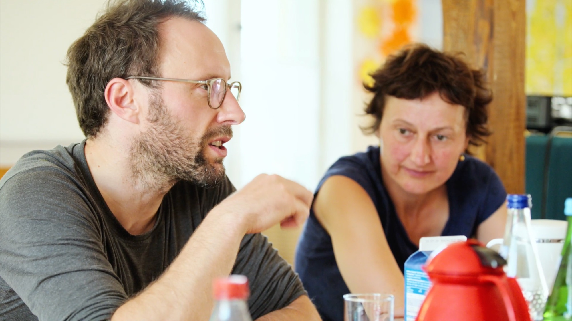 Ein Mann im Gespräch mit einer Frau an einem Tisch mit Getränken